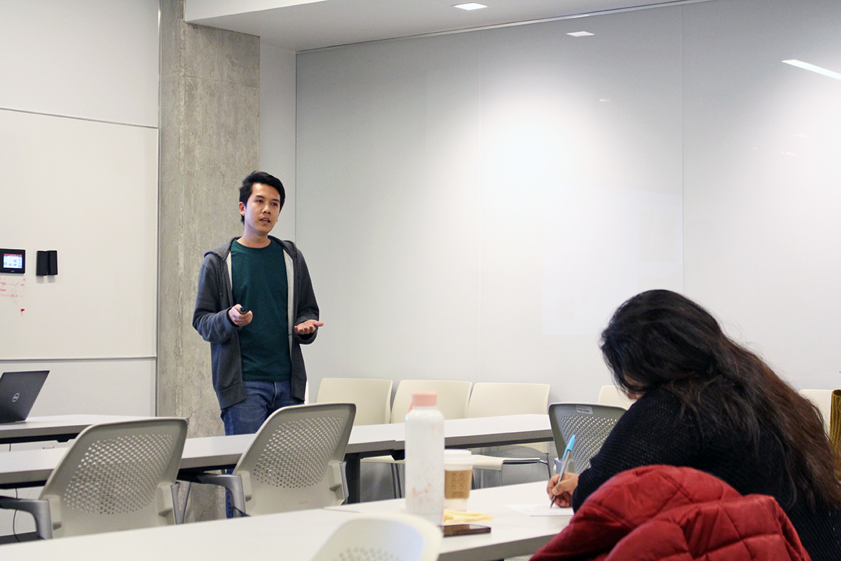 Ekkachai Khwanbua standing and presenting about his work at the front of a classroom of students.